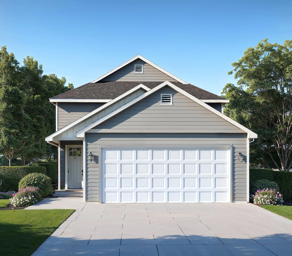 traditional home with driveway, an attached garage, and a shingled roof