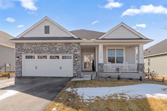 view of front of house with aphalt driveway, stone siding, a porch, and an attached garage