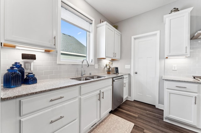 kitchen with light stone countertops, dark wood finished floors, dishwasher, white cabinetry, and a sink