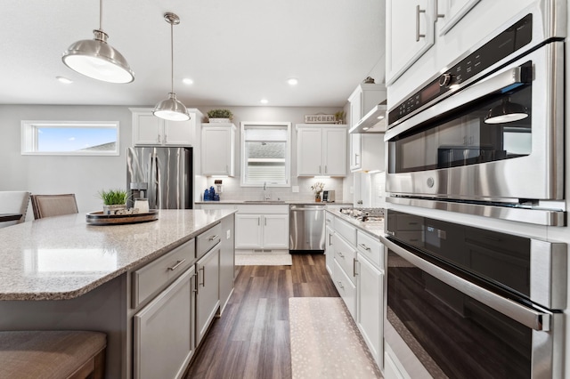 kitchen with decorative backsplash, dark wood-style floors, white cabinets, stainless steel appliances, and a sink