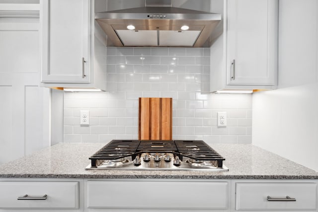 kitchen with stainless steel gas cooktop, white cabinetry, wall chimney range hood, and tasteful backsplash