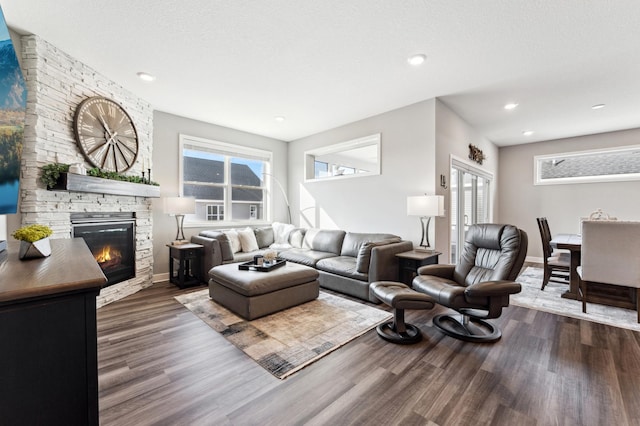 living area featuring dark wood finished floors, a stone fireplace, recessed lighting, and a textured ceiling