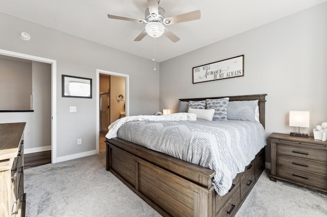 bedroom featuring ceiling fan, ensuite bath, baseboards, and light carpet