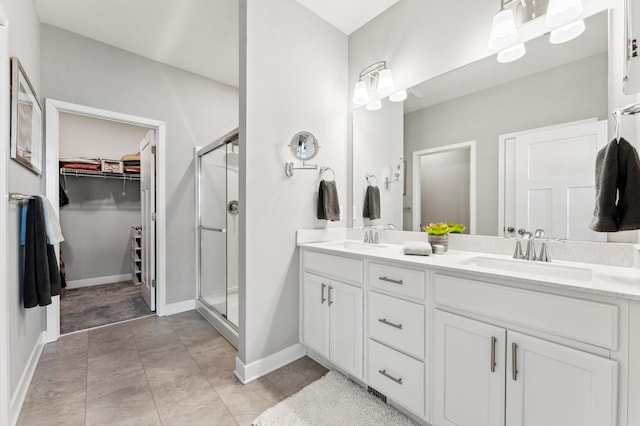 full bath featuring a walk in closet, double vanity, a stall shower, and a sink