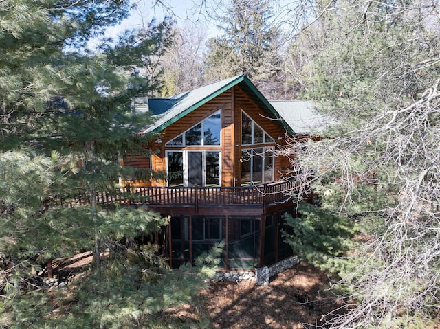 back of property with faux log siding, a wooden deck, and a sunroom