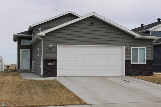 view of front of property featuring concrete driveway, an attached garage, and stone siding