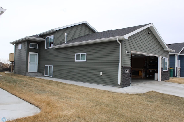 exterior space with a lawn, driveway, entry steps, a shingled roof, and a garage