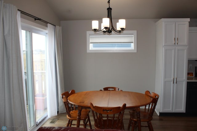 dining space with a chandelier, lofted ceiling, visible vents, and wood finished floors