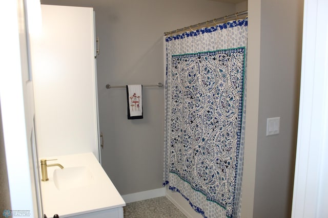 bathroom featuring a shower with shower curtain, baseboards, and vanity