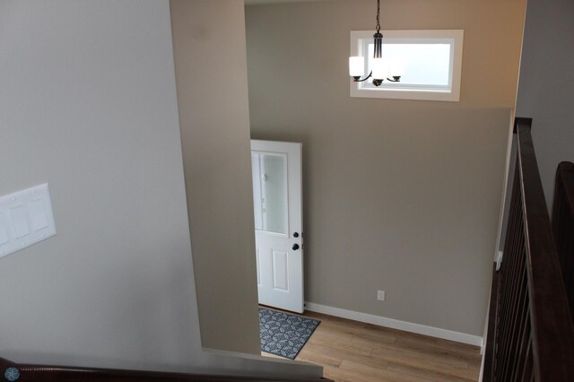 foyer featuring an inviting chandelier, baseboards, and light wood finished floors