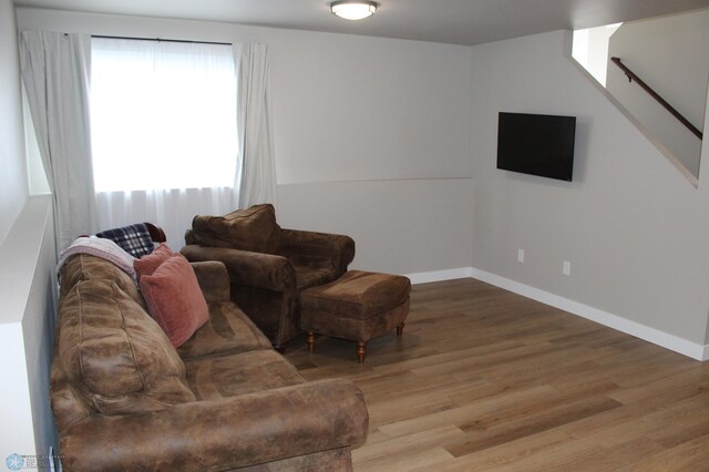 living room featuring stairway, baseboards, and wood finished floors