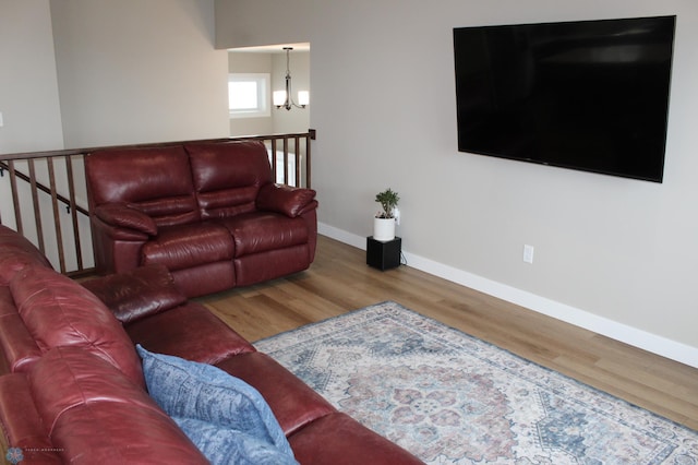 living room featuring a notable chandelier, baseboards, and wood finished floors