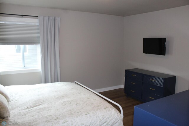 bedroom with dark wood-style floors and baseboards