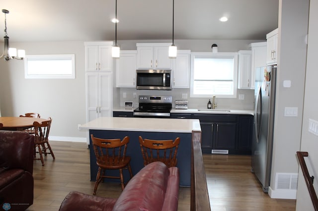 6746 Joseph St, Horace, ND 58047 - kitchen with stainless steel appliances, a sink, light countertops, wood finished floors, and white cabinetry