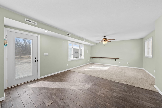 unfurnished living room featuring visible vents, baseboards, a ceiling fan, and wood finished floors