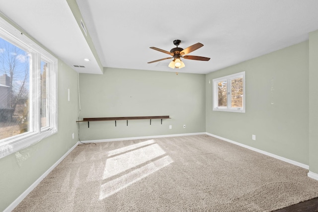 carpeted spare room with visible vents, baseboards, and ceiling fan