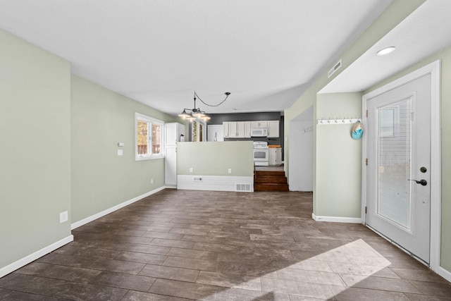 unfurnished living room with a chandelier, visible vents, baseboards, and dark wood-style floors