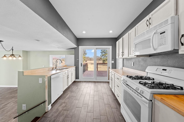 kitchen with dark wood-type flooring, a sink, white cabinetry, white appliances, and baseboards