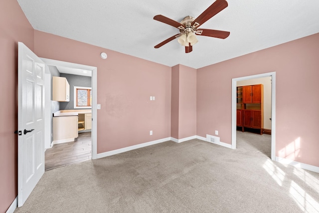 unfurnished bedroom featuring visible vents, light colored carpet, a walk in closet, and baseboards