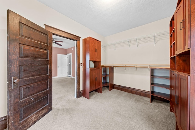 walk in closet featuring light colored carpet and ceiling fan