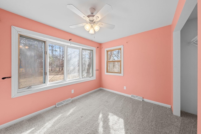 carpeted spare room featuring a ceiling fan, baseboards, and visible vents