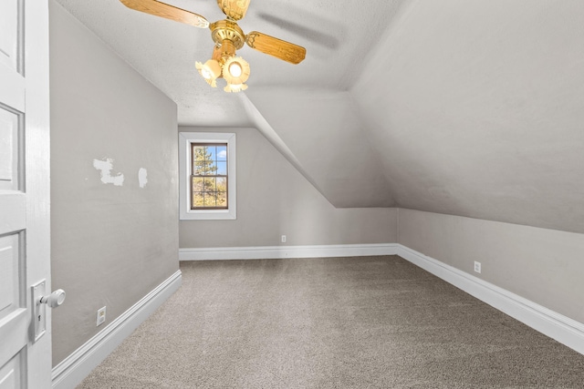 additional living space with a ceiling fan, a textured ceiling, carpet floors, baseboards, and vaulted ceiling