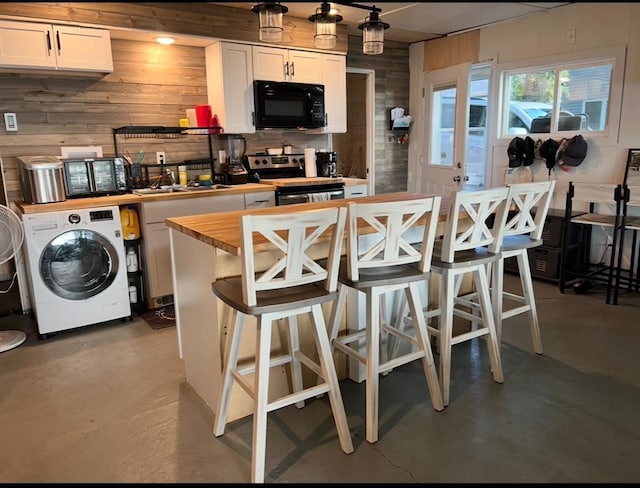 kitchen with stainless steel electric range oven, wooden walls, wooden counters, washer / dryer, and black microwave