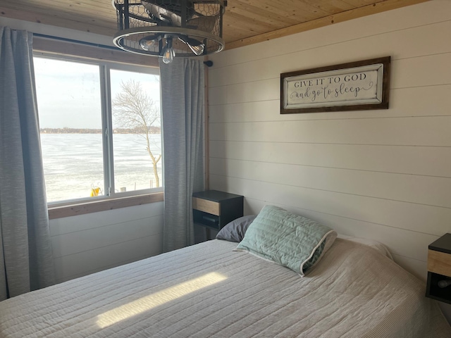 bedroom with a water view, wooden walls, and wood ceiling