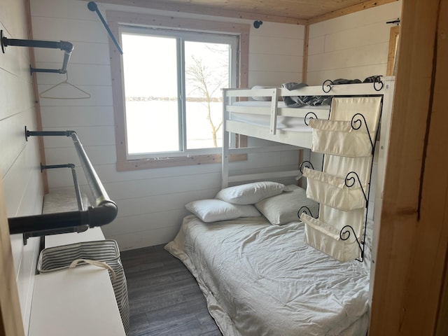 bedroom featuring dark wood finished floors and wood walls