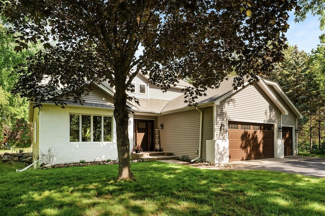 view of front of home featuring brick siding, a shingled roof, a front yard, a garage, and driveway