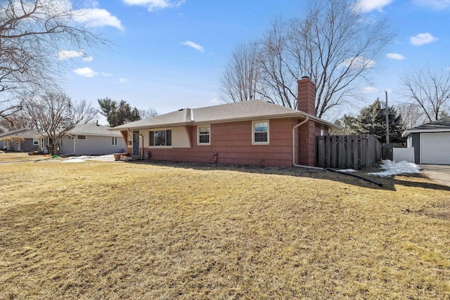 exterior space featuring fence, roof with shingles, an outdoor structure, a front yard, and a chimney