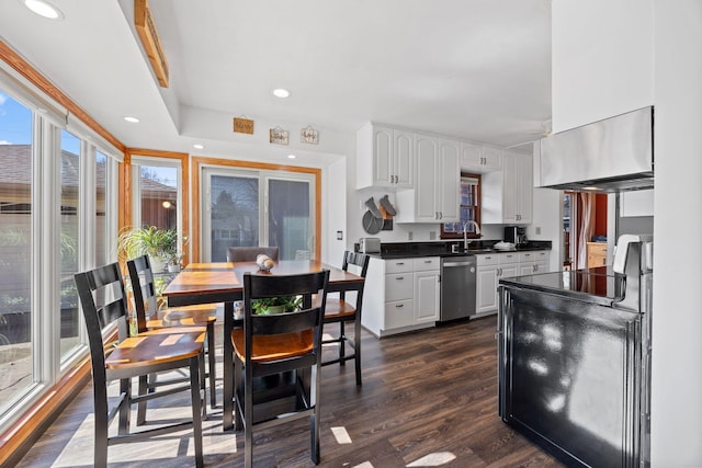 kitchen with stainless steel dishwasher, dark countertops, dark wood finished floors, exhaust hood, and white cabinets