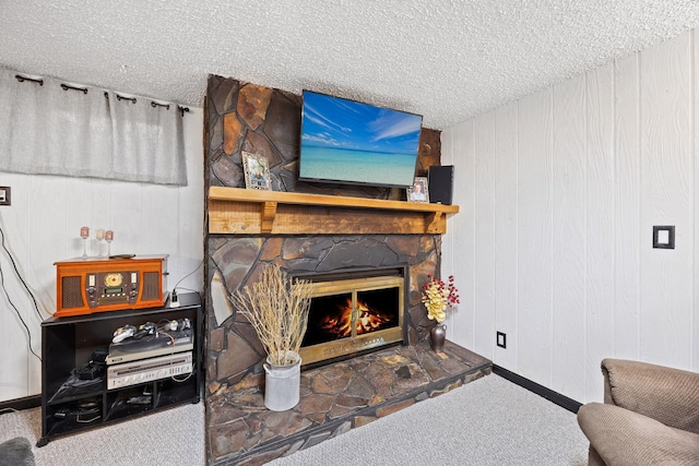 living area featuring a stone fireplace, carpet floors, and a textured ceiling