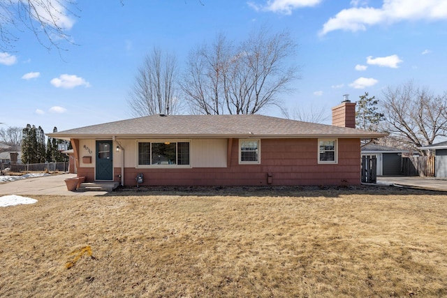 single story home featuring a chimney, roof with shingles, a front yard, and fence