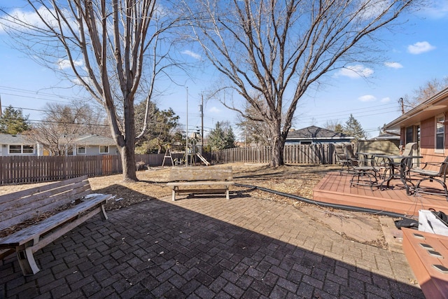 view of patio with outdoor dining space, a playground, and a fenced backyard