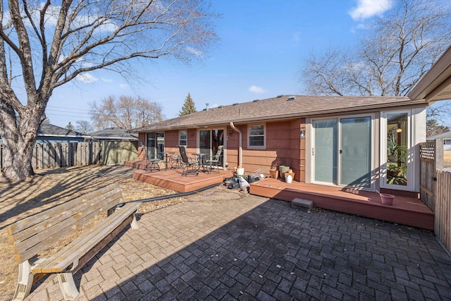 back of house with a wooden deck, a patio, a shingled roof, and fence