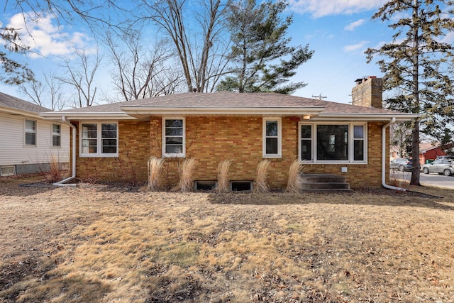 rear view of house with brick siding and a chimney