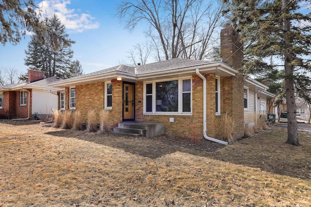 ranch-style house featuring brick siding and a chimney