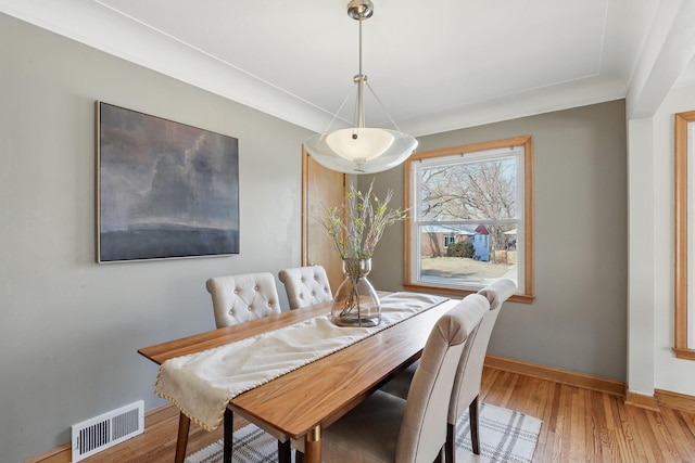 dining space with wood finished floors, visible vents, and baseboards