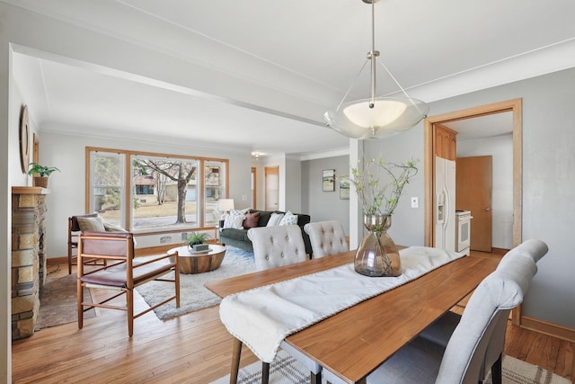 dining area featuring light wood-style floors, baseboards, and ornamental molding