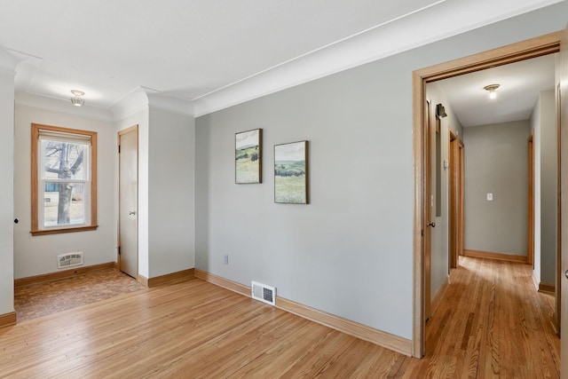 interior space with crown molding, light wood-style floors, visible vents, and baseboards