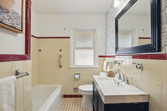 bathroom with visible vents, toilet, vanity, wainscoting, and tile walls