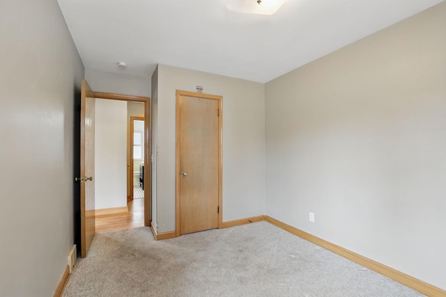 unfurnished bedroom featuring baseboards and light carpet