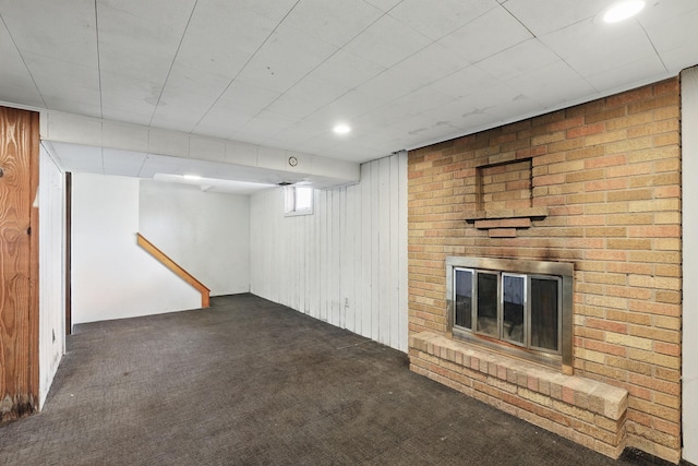 basement featuring a fireplace and dark carpet