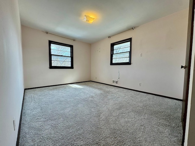 carpeted empty room with baseboards, plenty of natural light, and visible vents