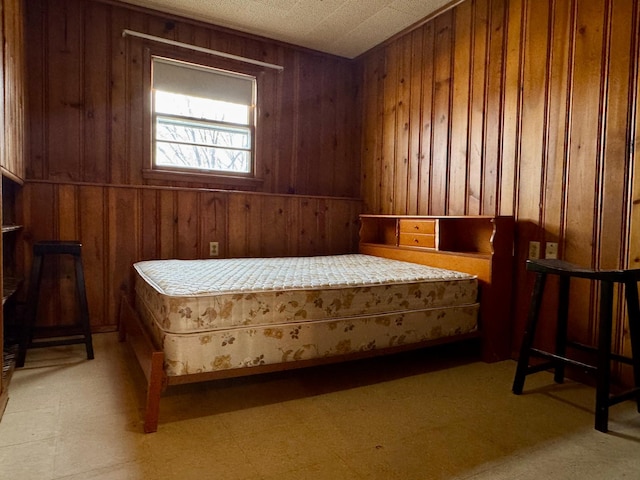 bedroom featuring wooden walls and light floors