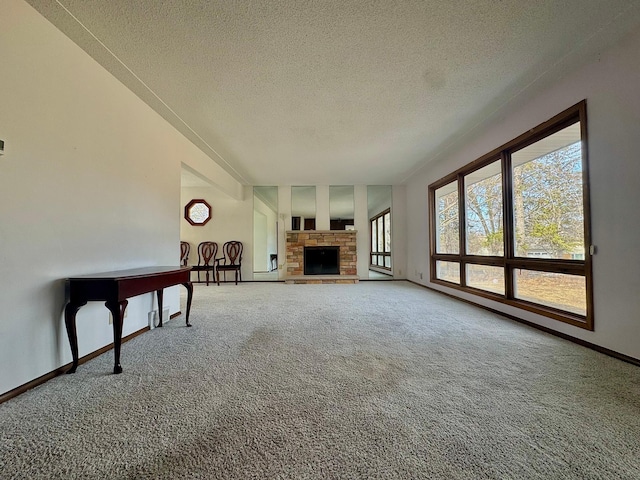 unfurnished living room featuring a textured ceiling, carpet, baseboards, and a fireplace with raised hearth