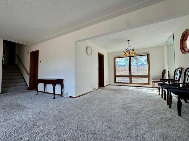 living area featuring baseboards, visible vents, carpet floors, stairs, and a textured ceiling