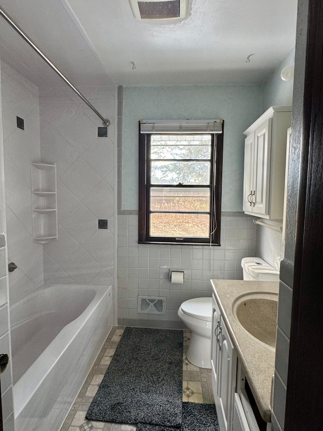 full bath with vanity, visible vents, shower / tub combination, tile walls, and toilet