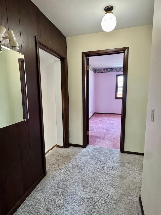 hall featuring carpet flooring and baseboards